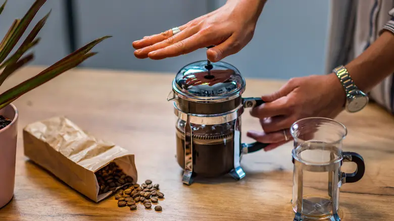 coffee beans next to French press being plunged